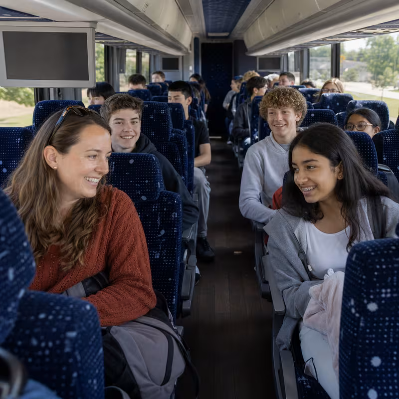 Group boarding a white charter bus for School Transportation transportation in San Jose